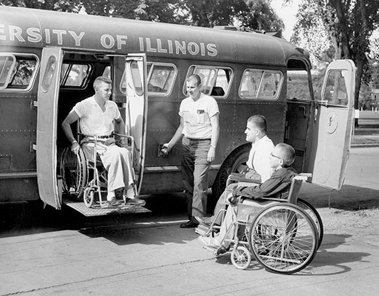 Students using a wheelchair lift to exit a bus in 1955